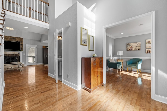 hallway featuring light hardwood / wood-style floors, a high ceiling, and ornamental molding