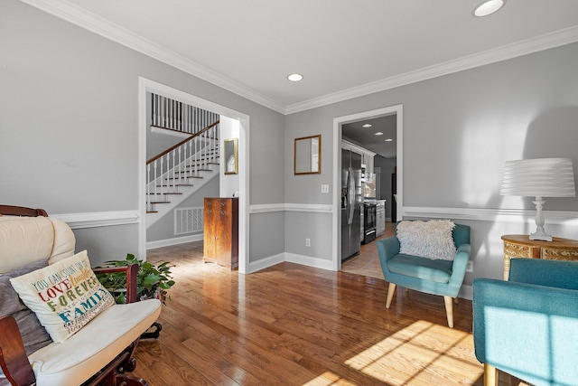 living area with hardwood / wood-style floors and ornamental molding