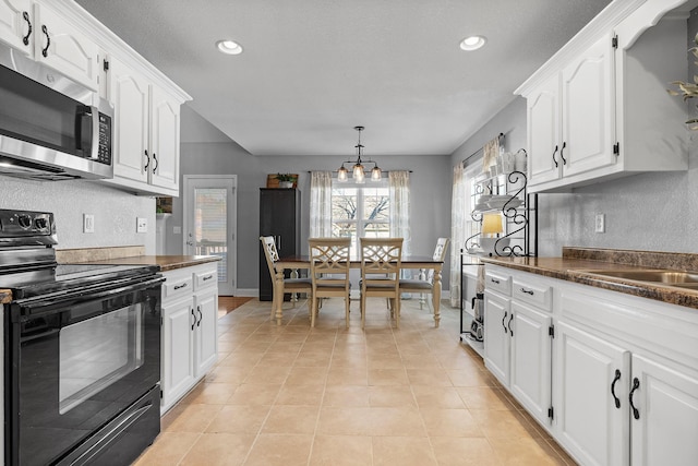 kitchen featuring white cabinets, decorative light fixtures, black range with electric stovetop, and a chandelier