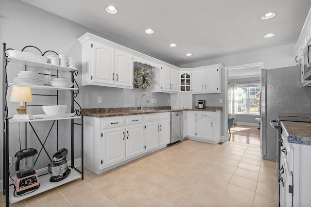 kitchen with stainless steel microwave, sink, white cabinets, and light tile patterned floors