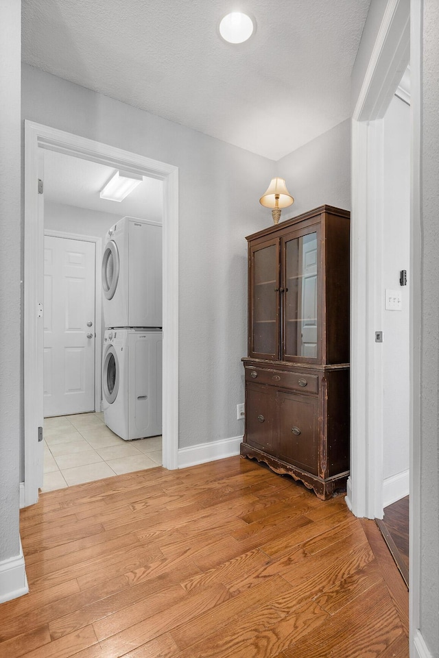 clothes washing area featuring light wood-type flooring and stacked washer and dryer