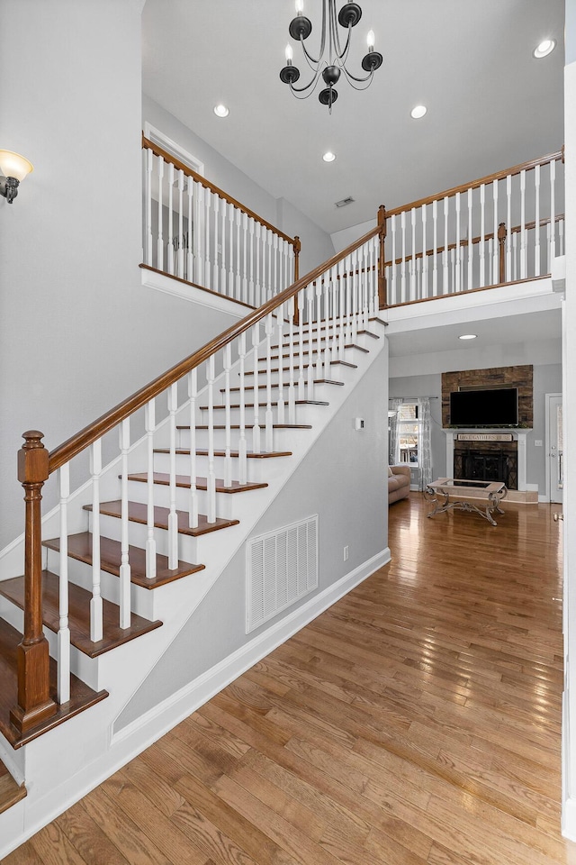 stairway with hardwood / wood-style floors, a fireplace, and a chandelier