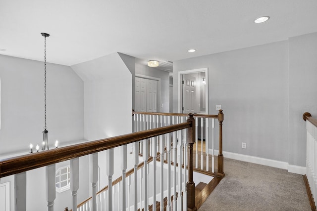 hall with carpet flooring, lofted ceiling, and an inviting chandelier