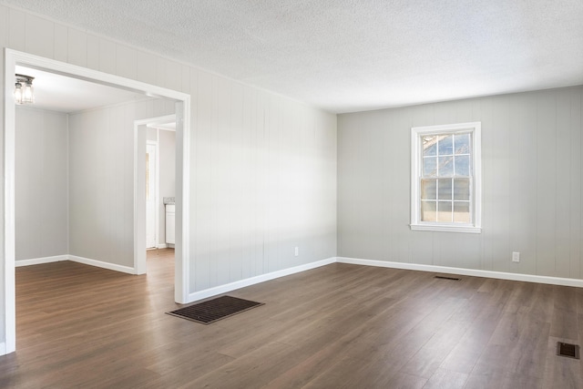 unfurnished room with dark hardwood / wood-style flooring and a textured ceiling