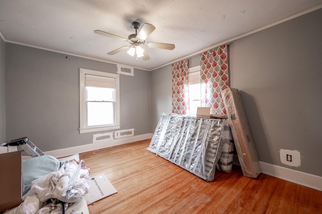 bedroom featuring multiple windows, ceiling fan, wood-type flooring, and ornamental molding