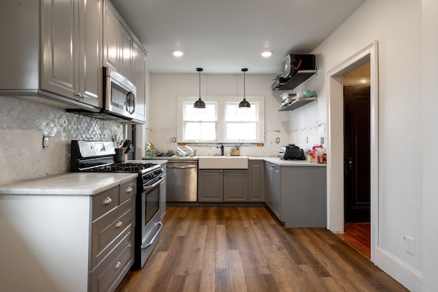 kitchen featuring gray cabinetry, sink, stainless steel appliances, dark wood-type flooring, and decorative light fixtures