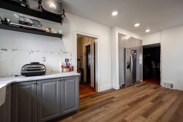 kitchen with gray cabinets, stainless steel fridge with ice dispenser, dark hardwood / wood-style flooring, and decorative backsplash