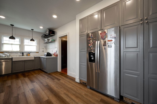 kitchen featuring dark wood-type flooring, hanging light fixtures, sink, gray cabinets, and appliances with stainless steel finishes