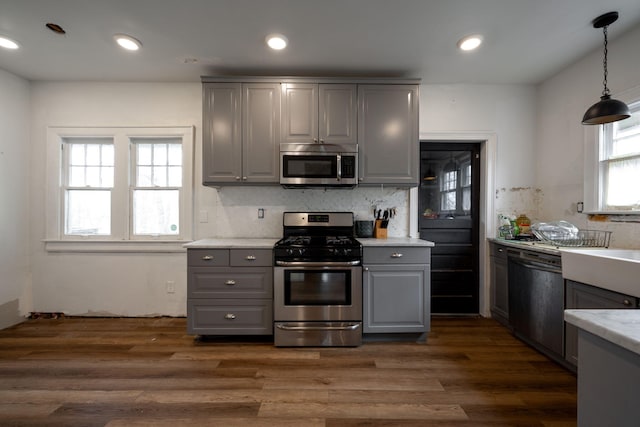 kitchen with gray cabinetry, decorative backsplash, pendant lighting, and stainless steel appliances