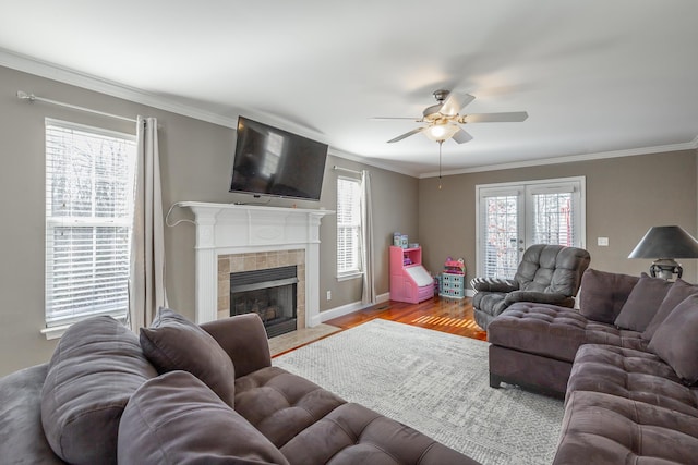 living room featuring ceiling fan, a fireplace, crown molding, and light wood-type flooring