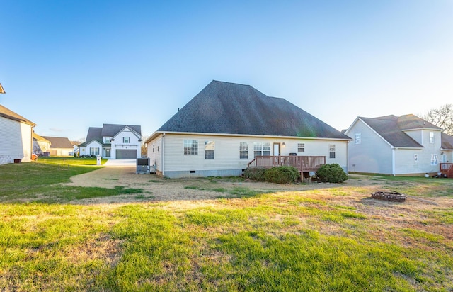 back of house featuring central air condition unit, an outdoor fire pit, a lawn, and a wooden deck