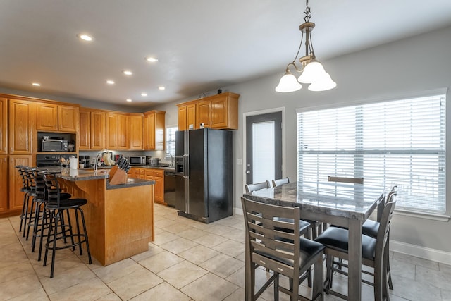 kitchen with dark stone counters, sink, black appliances, a center island with sink, and a chandelier