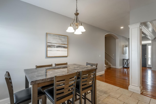 tiled dining space with decorative columns and a chandelier