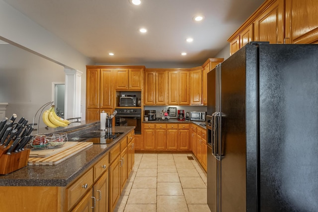 kitchen with light tile patterned flooring, dark stone counters, and black appliances