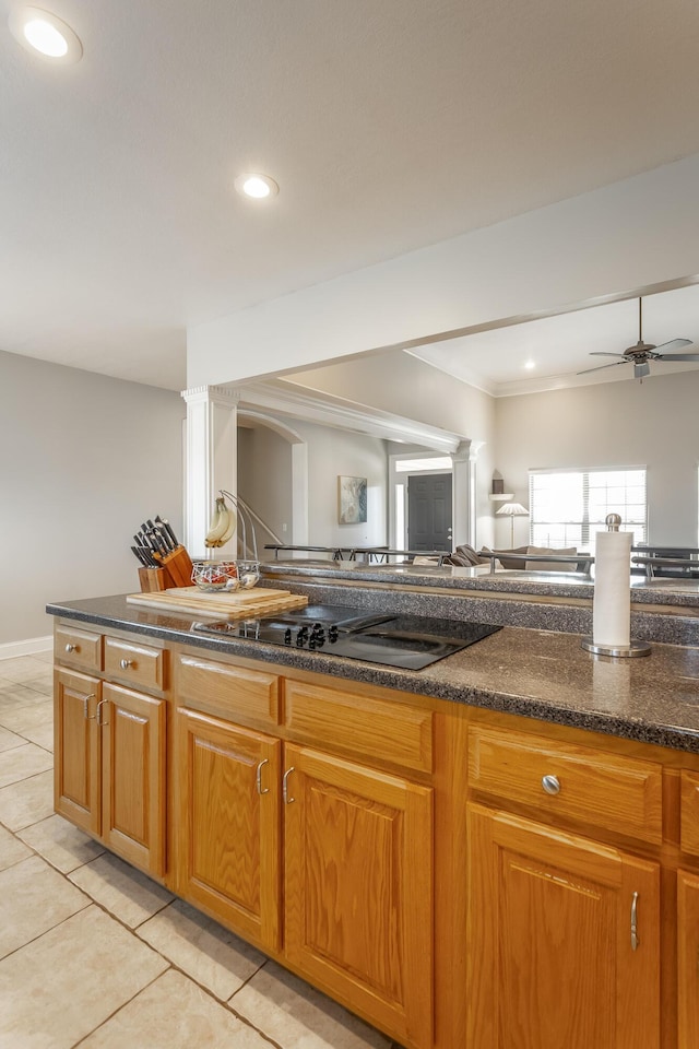 kitchen with black electric stovetop, light tile patterned floors, ceiling fan, and dark stone countertops