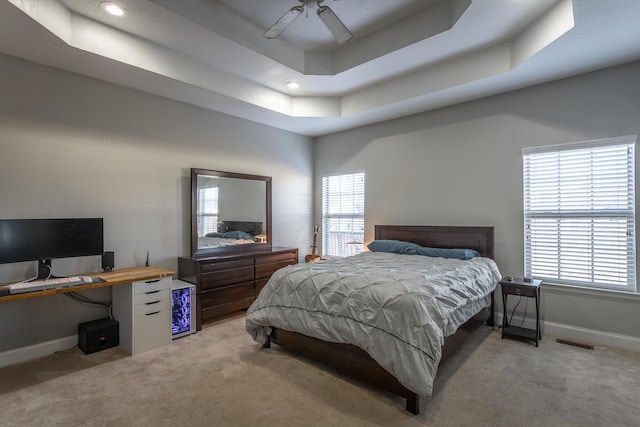 bedroom featuring ceiling fan, a raised ceiling, and light carpet