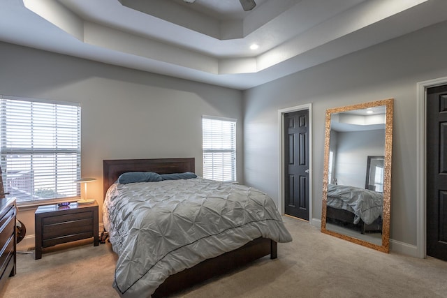 carpeted bedroom with a raised ceiling and ceiling fan