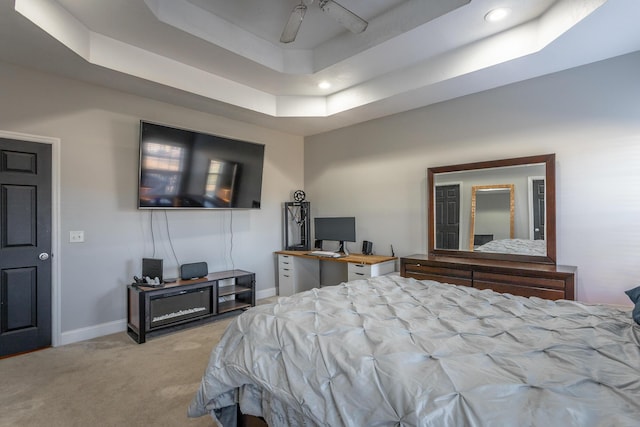 bedroom featuring a raised ceiling, ceiling fan, and light carpet