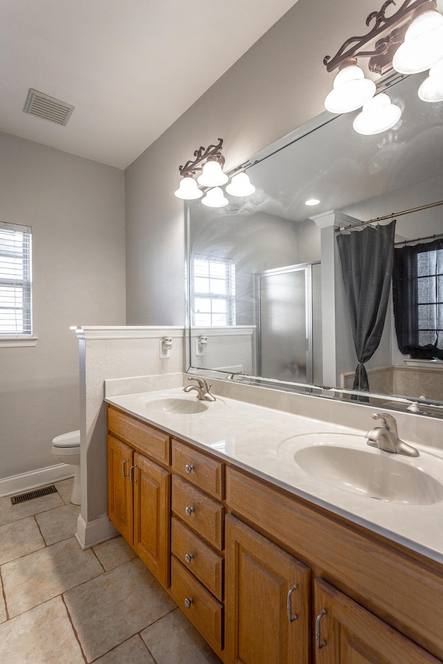 bathroom featuring tile patterned floors, a healthy amount of sunlight, toilet, and a shower with door