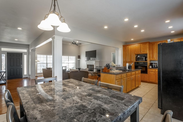 kitchen with ceiling fan, decorative columns, decorative light fixtures, a kitchen island, and black appliances