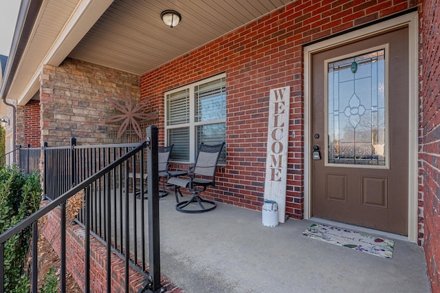 property entrance with a porch and brick siding