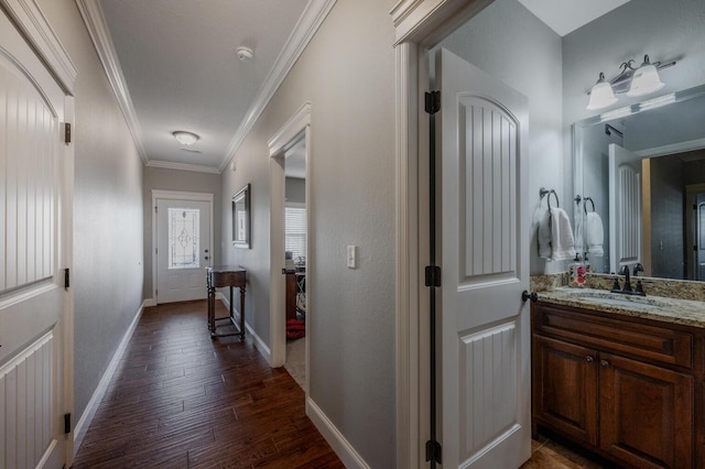 hall featuring baseboards, ornamental molding, dark wood finished floors, and a sink