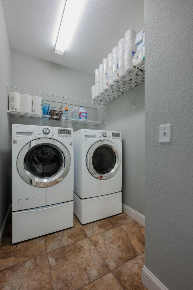 laundry room featuring laundry area, baseboards, a textured ceiling, and washing machine and clothes dryer