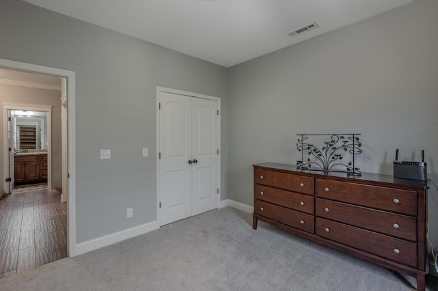 bedroom featuring baseboards, a closet, visible vents, and light colored carpet