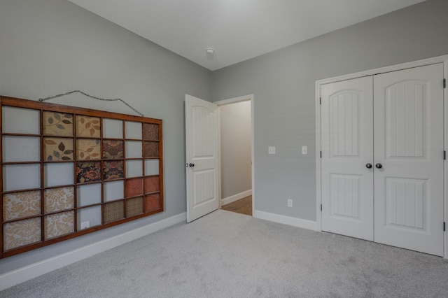 unfurnished bedroom with carpet floors, a closet, and baseboards