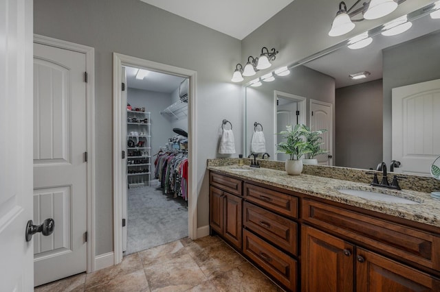 full bathroom with double vanity, a spacious closet, and a sink