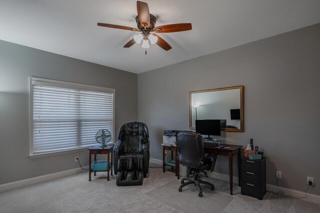 carpeted office space with ceiling fan and baseboards