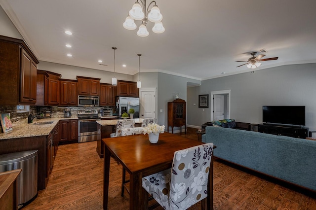 dining space with dark wood-style floors, recessed lighting, ornamental molding, and ceiling fan with notable chandelier