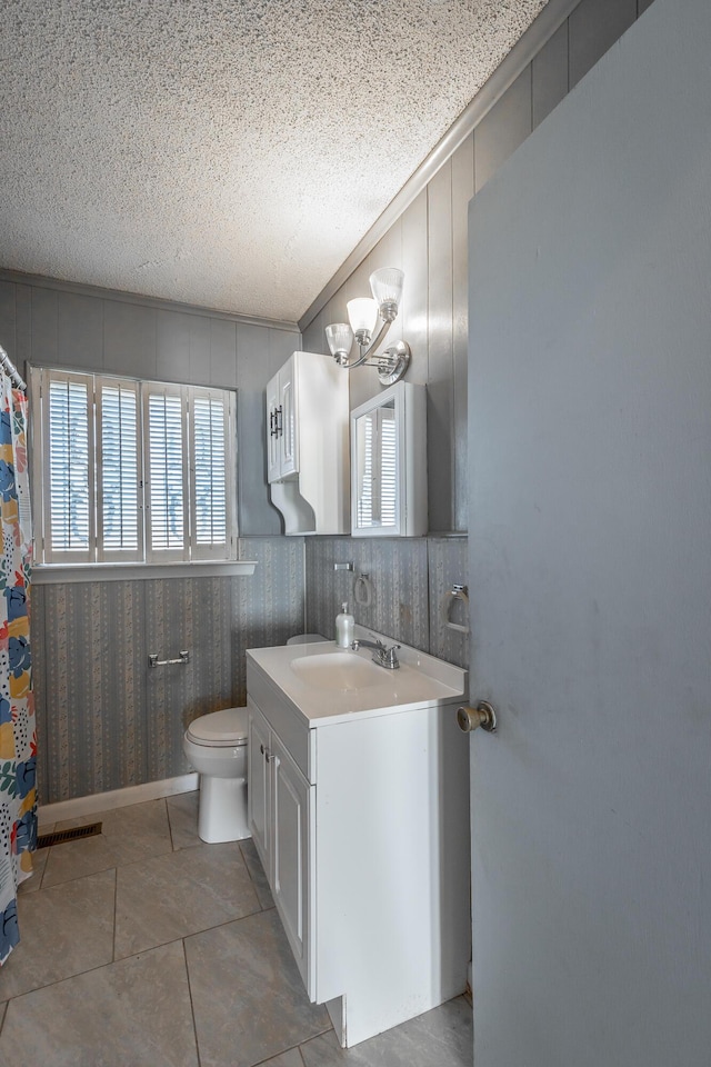 bathroom featuring toilet, vanity, a textured ceiling, ornamental molding, and a chandelier