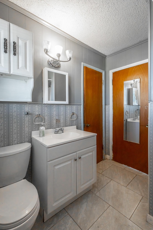 bathroom featuring toilet, vanity, tile patterned floors, and a textured ceiling