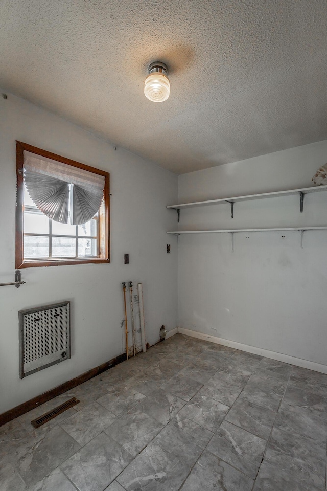 unfurnished room with a textured ceiling and heating unit