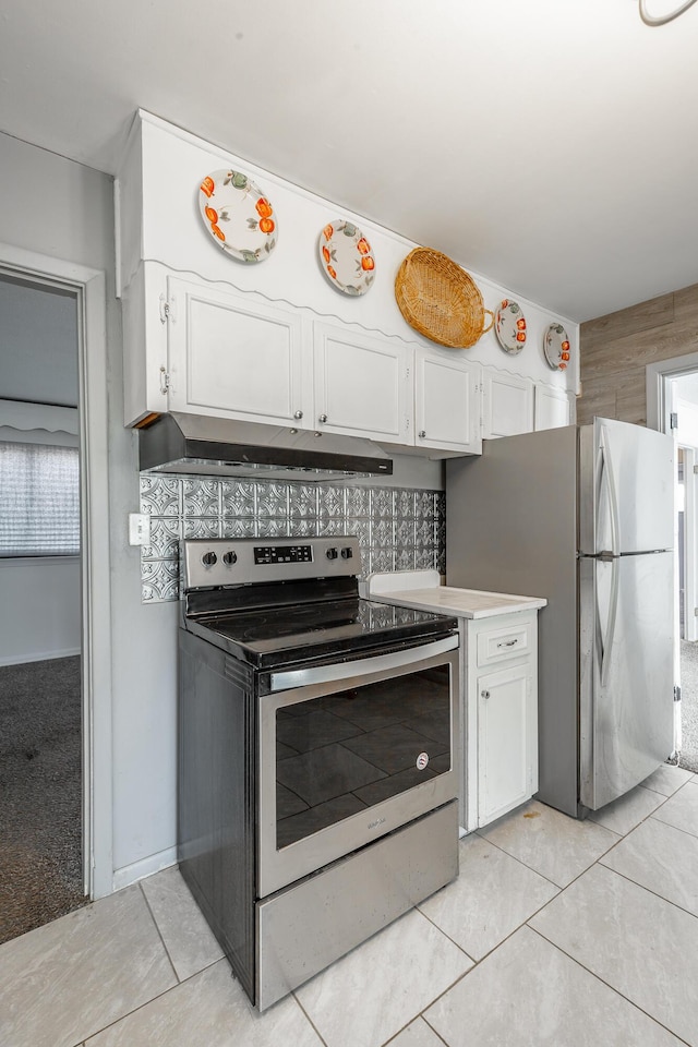 kitchen featuring light tile patterned floors, appliances with stainless steel finishes, decorative backsplash, and white cabinets