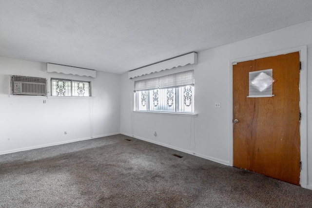 unfurnished room with carpet, a textured ceiling, and a wall mounted air conditioner