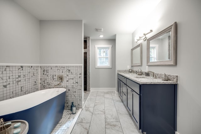 bathroom featuring vanity, a bathtub, and tile walls