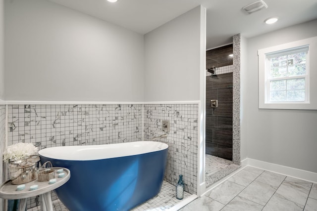 bathroom with separate shower and tub and tile walls