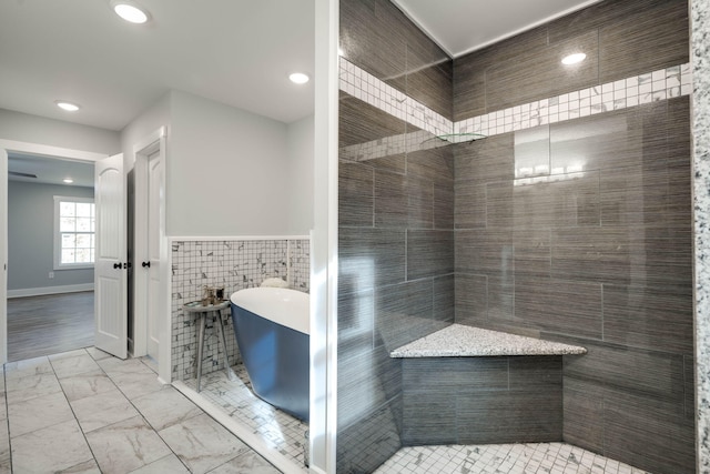 bathroom with shower with separate bathtub and tile walls