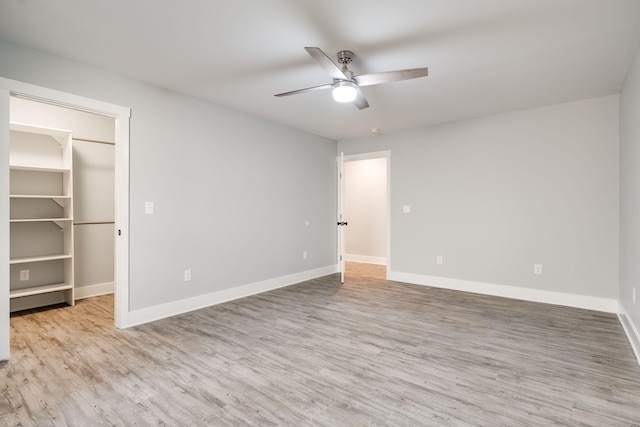 unfurnished bedroom with a walk in closet, ceiling fan, a closet, and light wood-type flooring