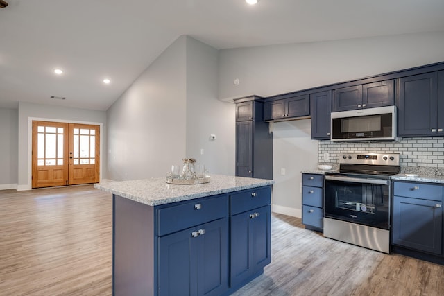 kitchen featuring light hardwood / wood-style flooring, light stone countertops, tasteful backsplash, a kitchen island, and stainless steel appliances