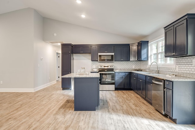 kitchen with light stone counters, sink, a kitchen island, and stainless steel appliances