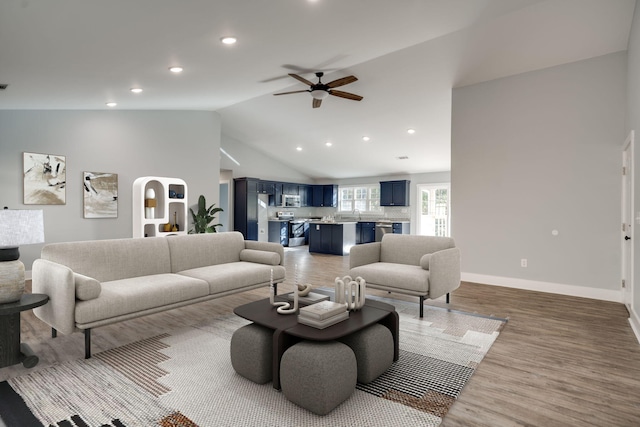 living room with ceiling fan, wood-type flooring, and lofted ceiling