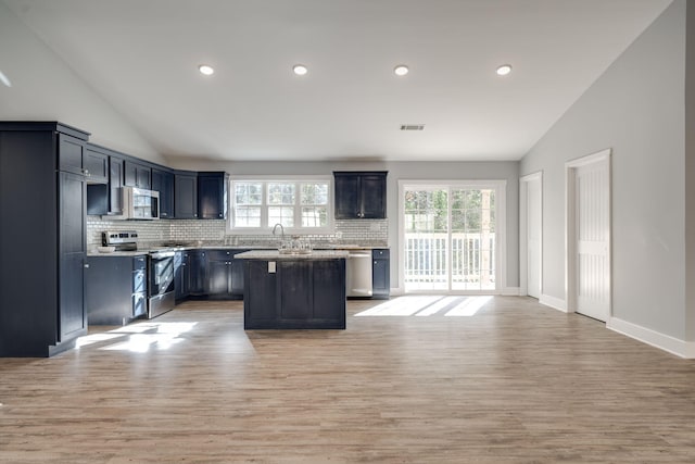 kitchen featuring tasteful backsplash, a center island, vaulted ceiling, and appliances with stainless steel finishes