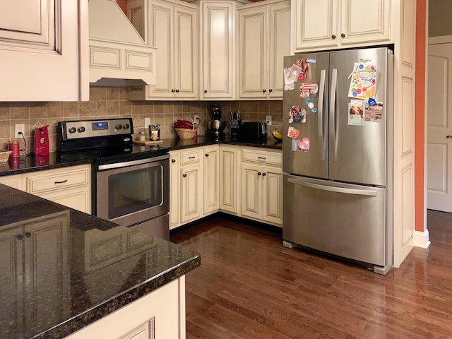 kitchen featuring custom exhaust hood, backsplash, dark wood-type flooring, cream cabinets, and stainless steel appliances