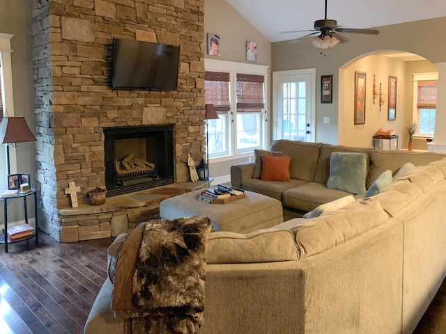 living room featuring lofted ceiling, a stone fireplace, ceiling fan, and dark hardwood / wood-style floors