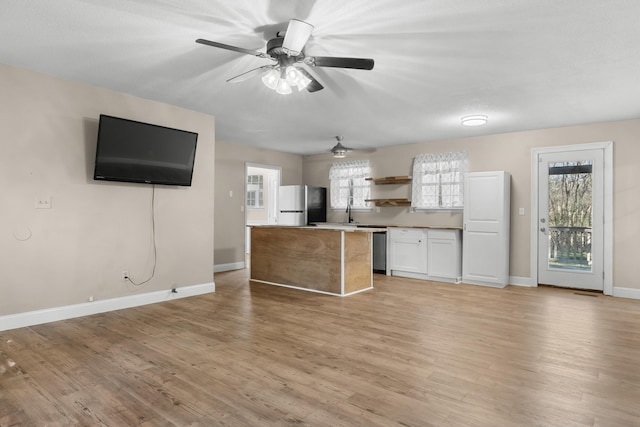 kitchen featuring light hardwood / wood-style flooring, stainless steel fridge, dishwashing machine, a kitchen island, and white cabinets