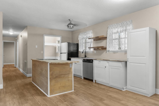 kitchen with a kitchen island, white cabinets, ceiling fan, stainless steel appliances, and light hardwood / wood-style flooring