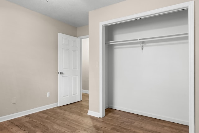 unfurnished bedroom featuring wood-type flooring, a closet, and a textured ceiling